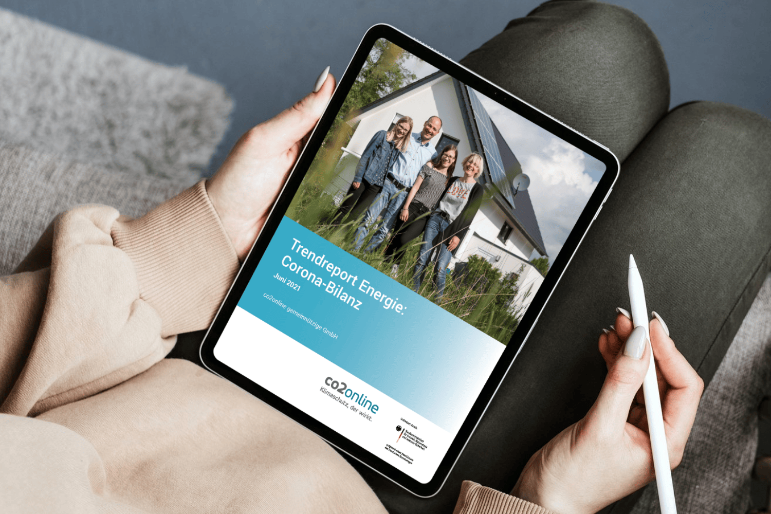 Auf dem Sofa sitzende Person scrollt durch den Trendreport Energie auf ihrem Tablet 