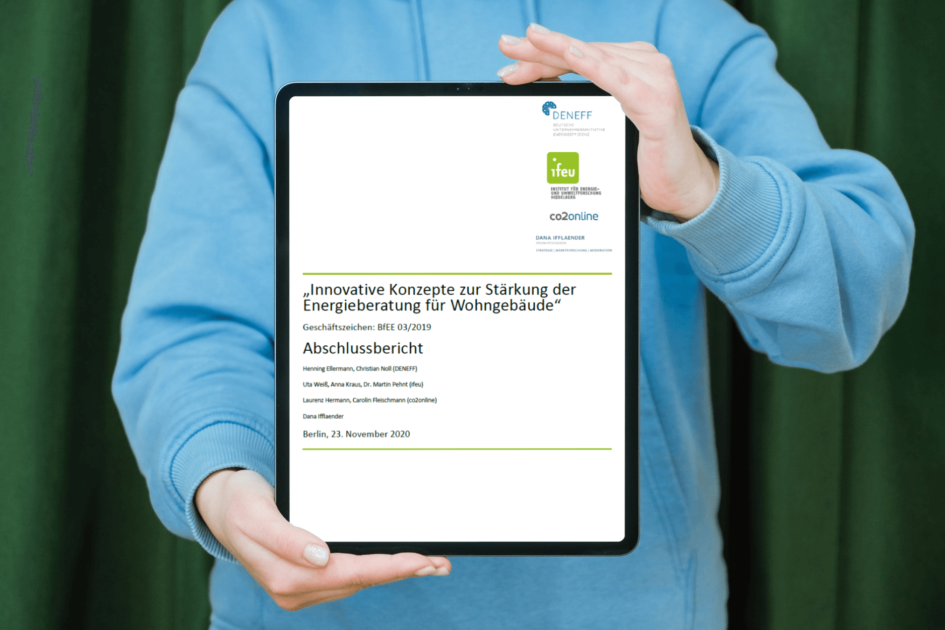 Person mit blauem Pullover hält vor sich ein Tablet mit der Publikation "Innovative Konzepte zur Stärkung der Energieberatung"