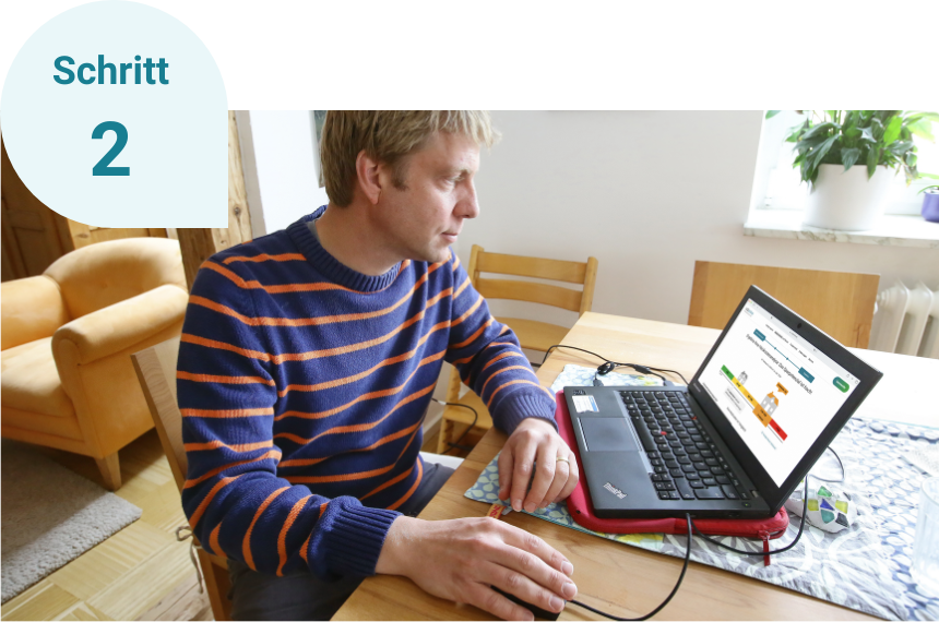 Schritt 2: Ein Mann sitzt an einem Tisch und schaut sich auf dem Laptop die Analyse des HeizChecks an.