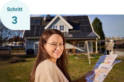 Schritt 3: Einfamilienhausbesitzerin steht im Garten mit einem Energieausweis in der Hand und lächelt in die Kamera.