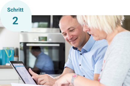 Schritt 2: Zwei Personen schauen sich die Ergebnisse des ModernisierungsChecks auf einem Tablet an.