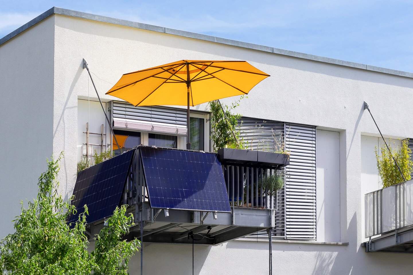 Balkon mit gelbem Schirm und Balkonkraftwerk