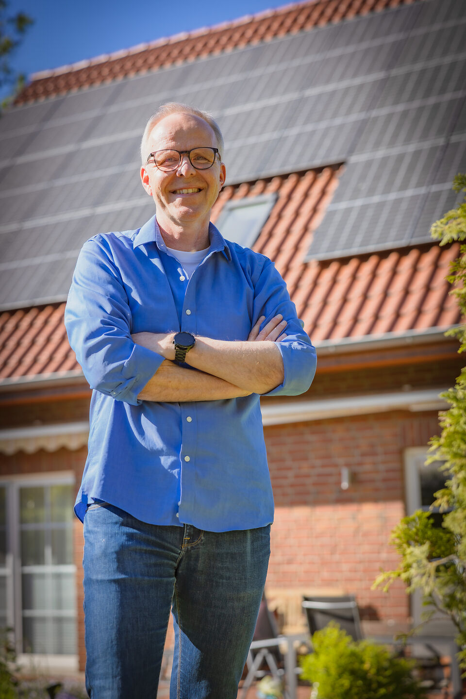 Ein älterer Mann vor einem Haus mit PV.