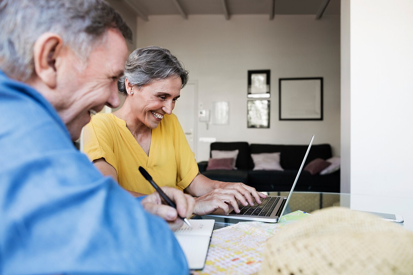 Seniorenpaar am Laptop schaut erfreut beim Planen und Berechnen