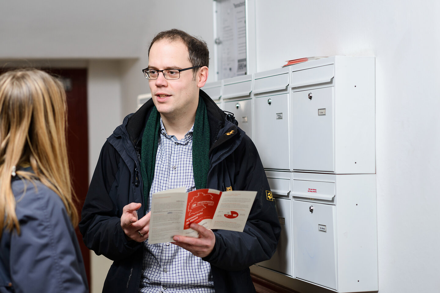 Zwei Personen vor Briefkästen im Gebäude.