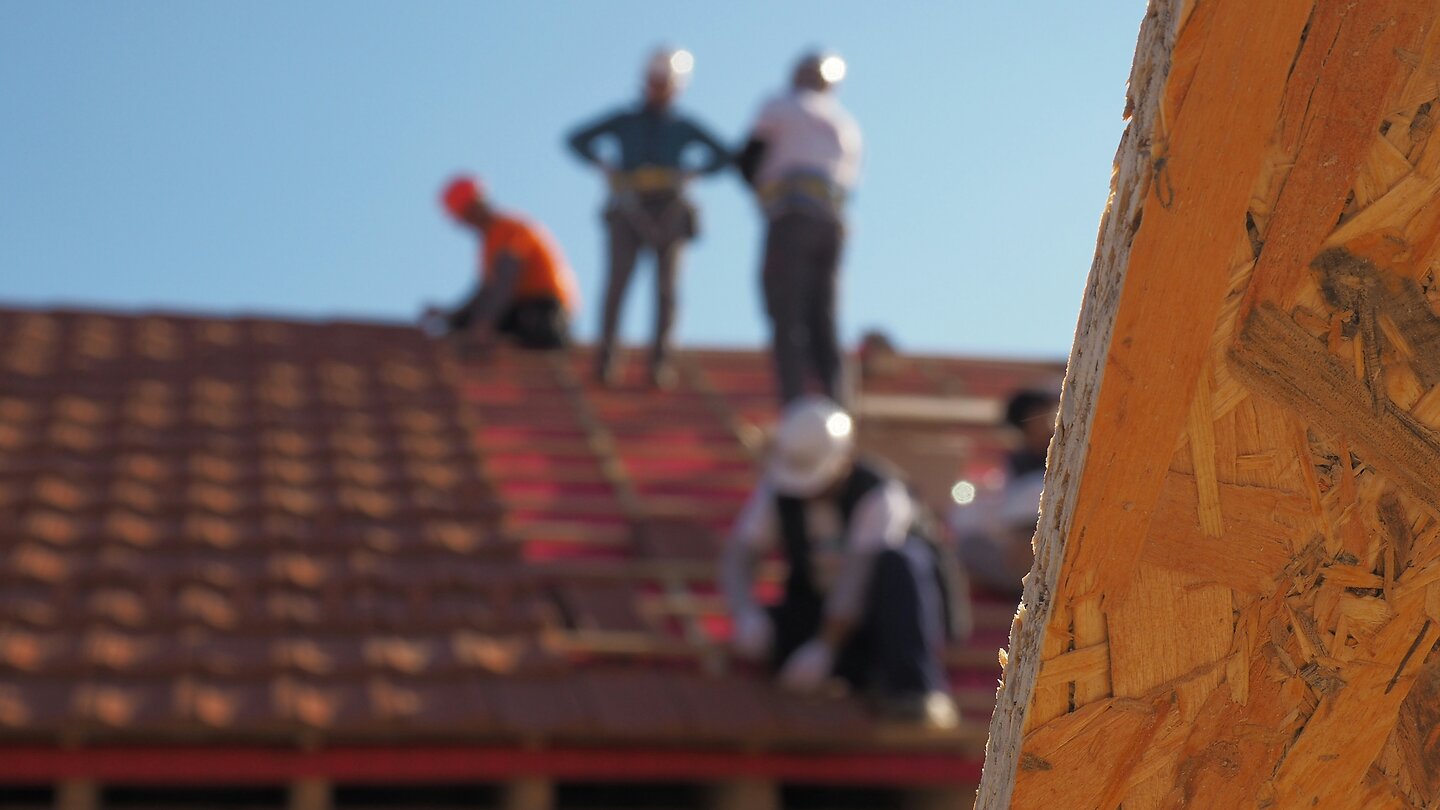 Mehrere Menschen arbeiten auf dem Dach eines Hauses