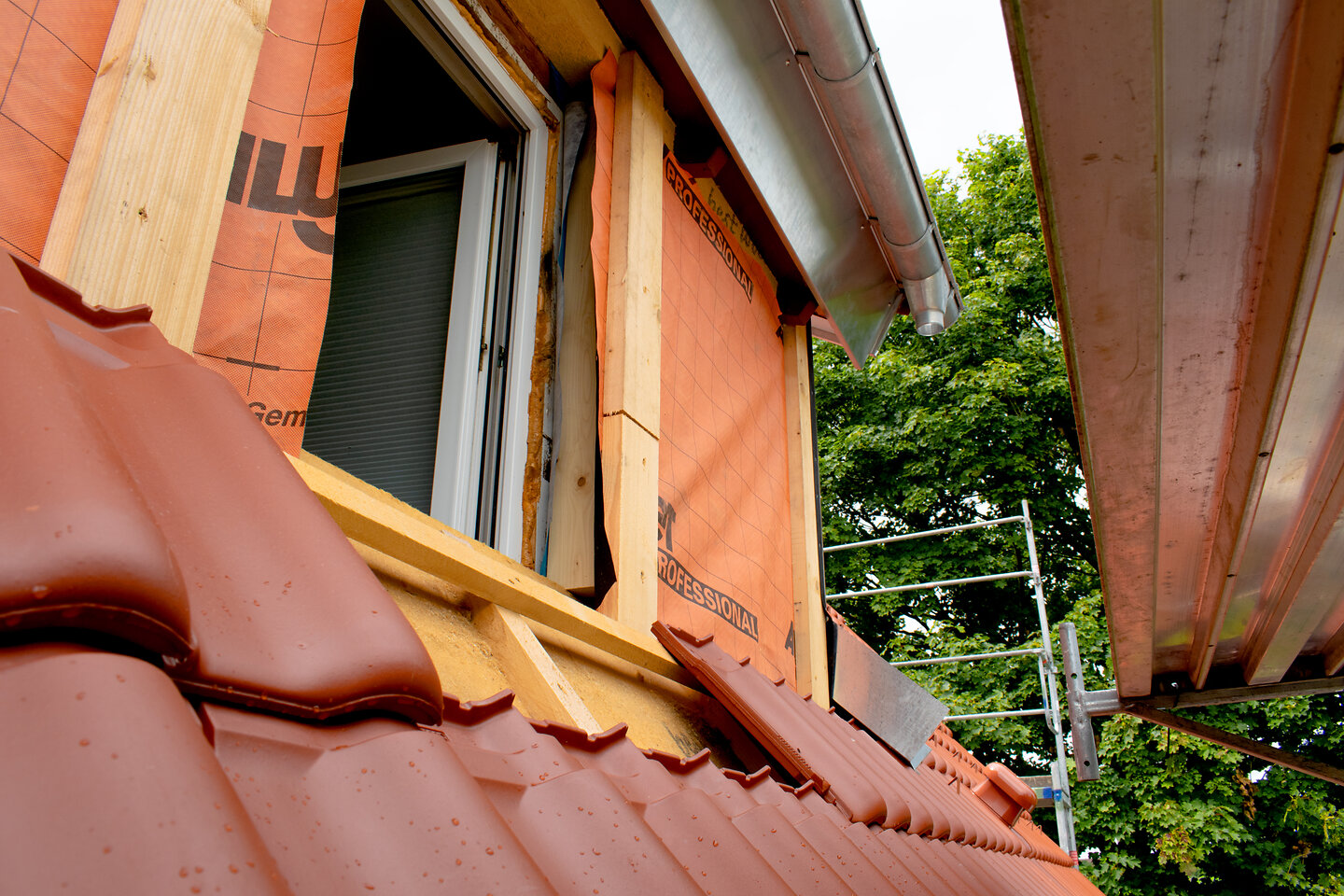 An einem Einfamilienhaus steht ein Gerüst, das Dach wird neu gedämmt.