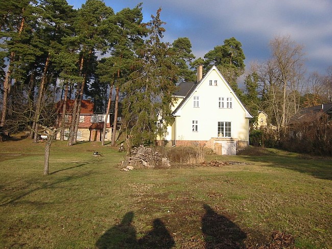 Einfamilienhaus vor der Sanierung: Wiese mit Nachbarhaus links, Haus rechts und Bäumen dazwischen und dahinter
