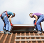 Installation Solarthermie: Männer heben einen Kollektor aufs Dach