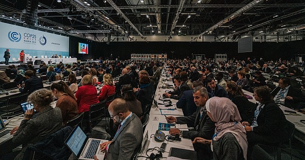 COP25 in Madrid: Delegierte an Tischen im Saal, links die Bühne
