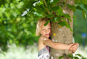 Maedchen umarmt Baum.