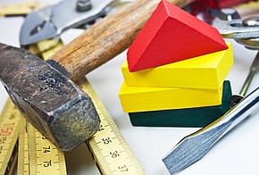 Symbolbild für KfW-Förderung: Hammer, Zollstock und andere Werkzeuge mit bunten Holz-Bausteinen