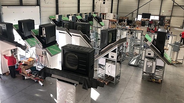 Serielle Sanierung: Haustechnik-Module der Factory zero in den Niederlanden (Werkshalle voller Wärmepumpen auf Dachelementen).