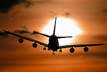 Ein Flugzeug fliegt in den Sonnenuntergang.