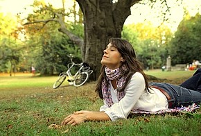 Eine Frau genießt die frische Luft im Park.