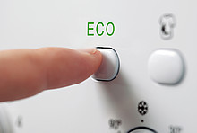 Finger drueckt Eco-Taste an Waschmaschine