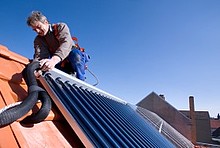 Handwerker mit Kollektor für Solarthermie auf Dach