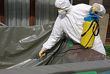 Mann in Schutzanzug entsorgt Asbest
