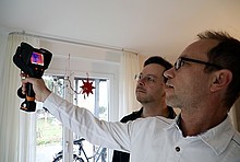Zwei Männer mit einer Wärmebildkamera in einem Wohngebäude